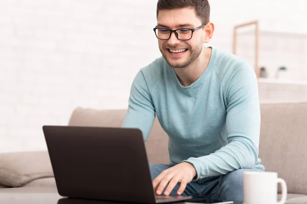 Freelancer met behulp van laptop werken online zitten op de bank thuis — Stockfoto