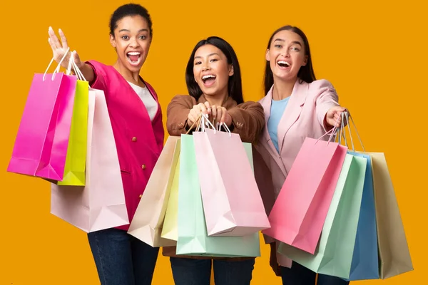 Tres mujeres emocionadas mostrando coloridas bolsas de compras, Studio Shot —  Fotos de Stock