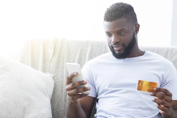 Africano americano hombre cheking su tarjeta de crédito saldo en línea — Foto de Stock