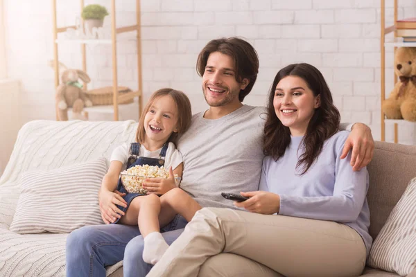 Família de três relaxante em casa, assistindo TV e comer pipoca — Fotografia de Stock