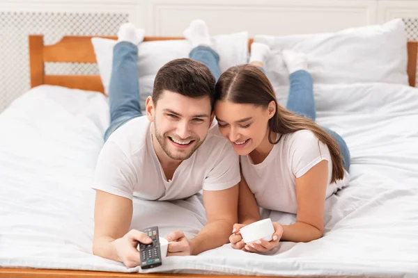 Cônjuges assistindo TV comutando canais relaxando na cama em casa — Fotografia de Stock