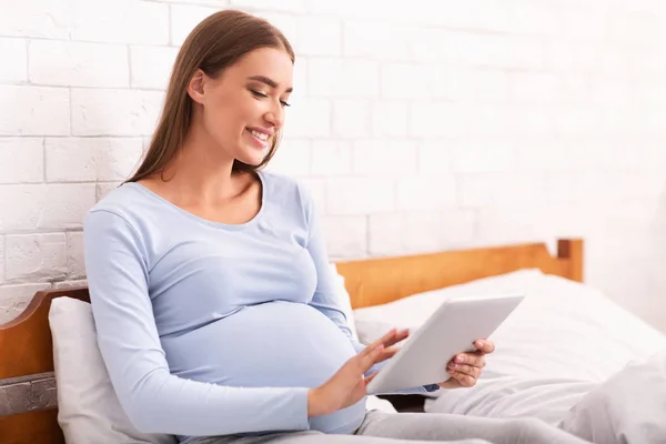 Boldog Terhes Lány Használja Tablet ül az ágyban otthon — Stock Fotó