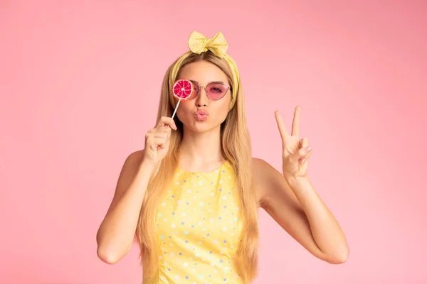 Spännande flicka som håller lollypop över rosa studio vägg — Stockfoto