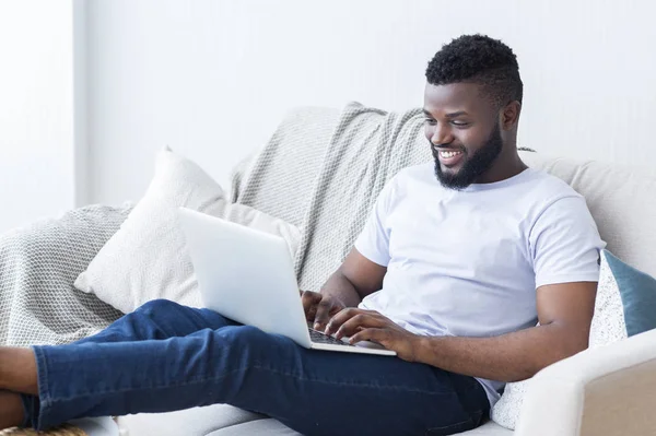 Młody czarny facet czat online na laptopie w domu — Zdjęcie stockowe