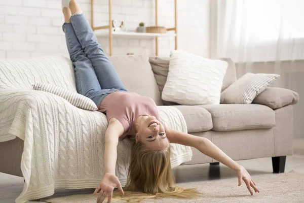 Ung kvinna ligger upp och ner på soffan hemma — Stockfoto