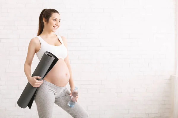 Wanita hamil aktif dalam pakaian olahraga memegang keset olahraga — Stok Foto