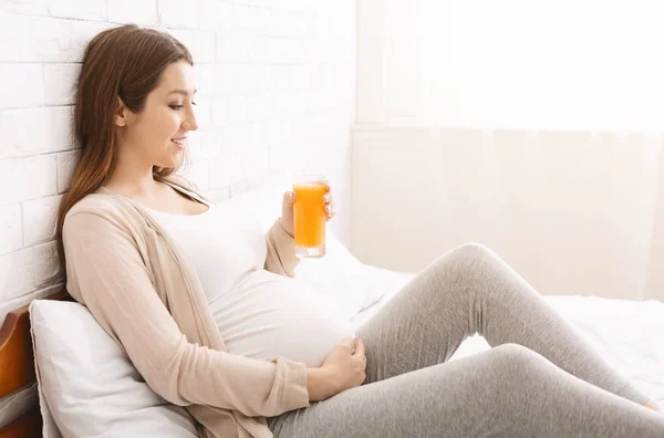 Hamile kadın taze yapılmış portakal suyuyla bardaktan zevk alıyor. — Stok fotoğraf