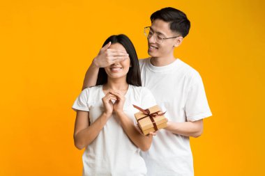 Neşeli Asyalı adam heyecanlı kız arkadaşına sürpriz yapıyor.