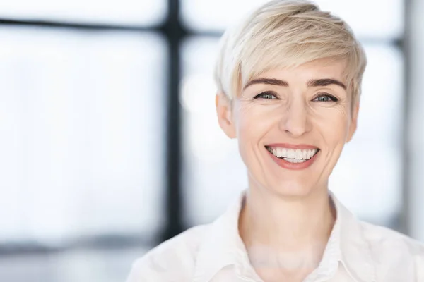 Mujer de negocios de mediana edad sonriendo a la cámara posando en la oficina moderna —  Fotos de Stock