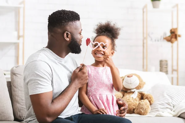 Lustige kleine schwarze Mädchen und Papa haben Accessoires auf Stöcken — Stockfoto