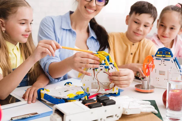 Escuela de ciencias. Profesor con alumnos construyendo robots — Foto de Stock