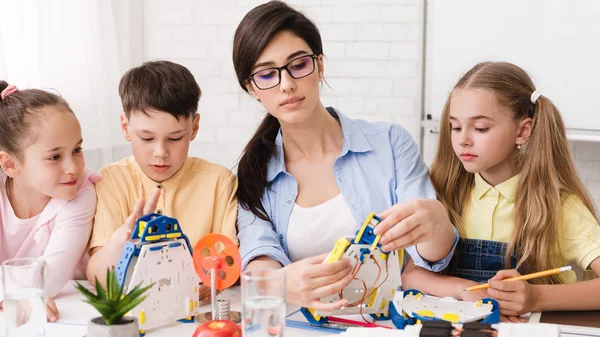 Diy and innovation concept. Pupils creating robots with teacher — Stock Photo, Image
