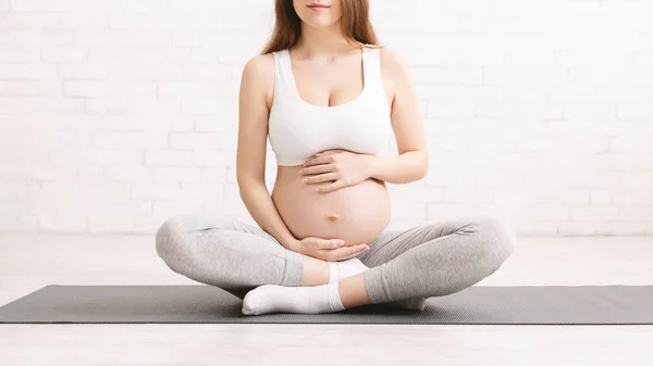 Wanita hamil dalam pakaian olahraga duduk di tikar yoga — Stok Foto