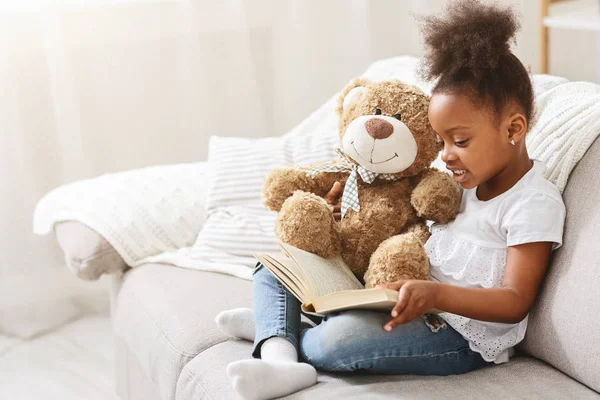 Niña negra leyendo cuento de hadas a su osito de peluche — Foto de Stock