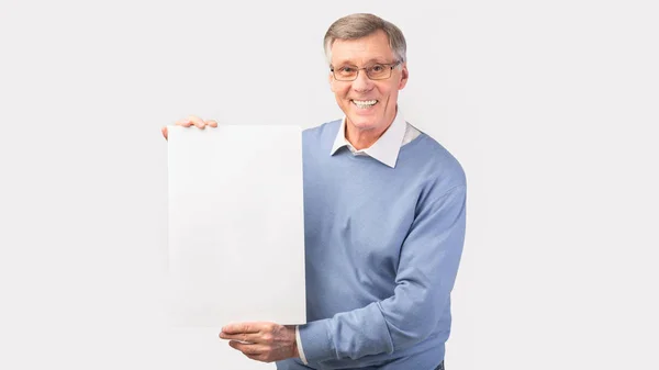 Hombre mayor alegre sosteniendo afiche en blanco, plano de estudio, panorámica — Foto de Stock
