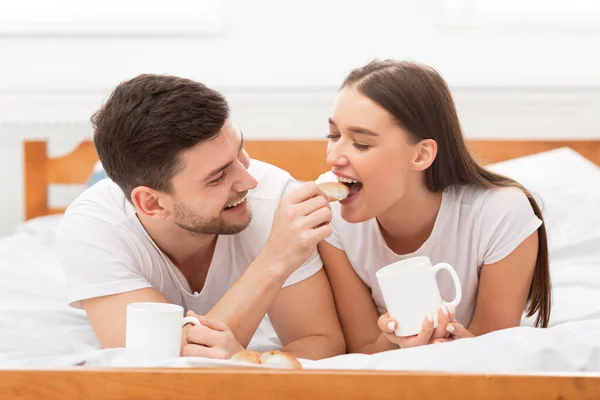 Amar casal alimentando uns aos outros tendo a data da manhã no quarto — Fotografia de Stock