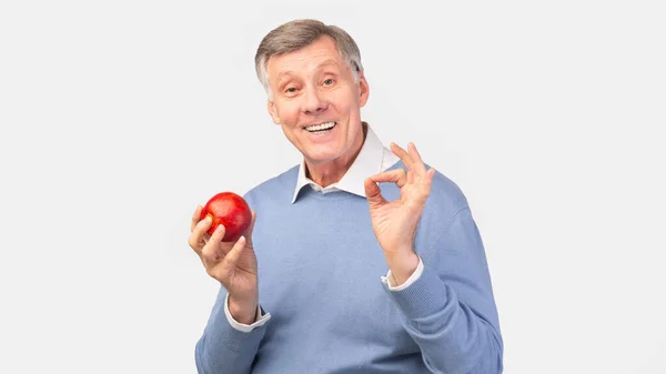 Senior Man Holding Apple Gesturing Okay Over Gray Background, Panorama — стокове фото