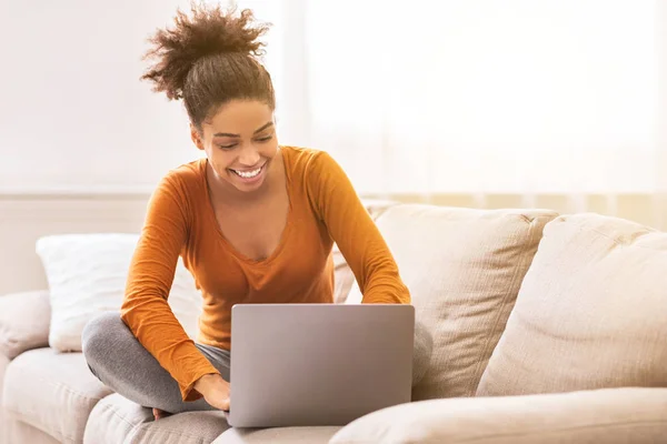 Afro vrouw werken op laptop zitten op bank thuis — Stockfoto