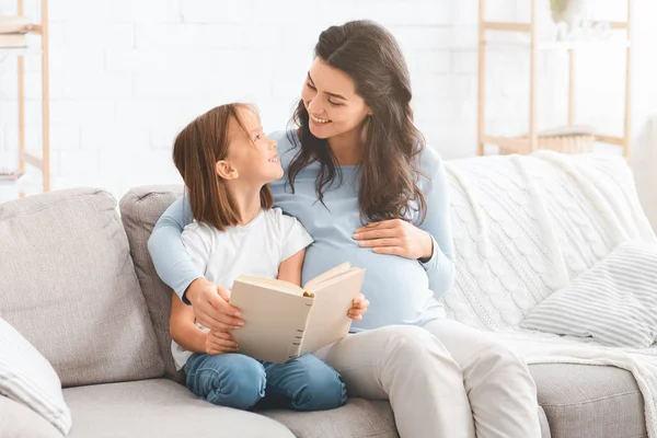 若いです妊娠中の女性読書おとぎ話へ彼女の小さな娘 — ストック写真