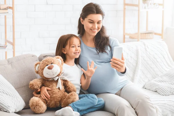 Tersenyum wanita hamil mengambil selfie dengan putri kecilnya — Stok Foto