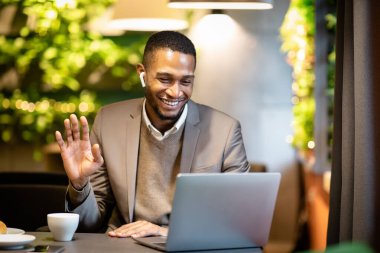 Gülümseyen siyah iş adamı aileye video çağrısı yapıyor.