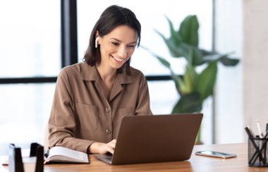 Dizüstü bilgisayar kullanarak müzik dinleyen gülümseyen kadın portresi