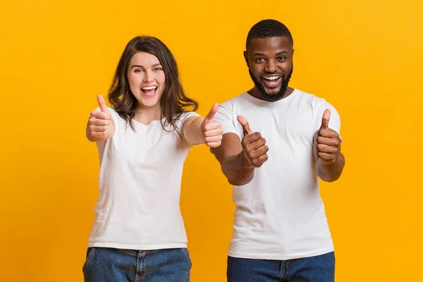 Joyful interracial couple gesturing thumbs up, recommending cool offer — 스톡 사진