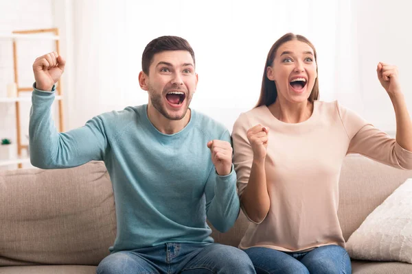 Casal animado assistindo esportes na TV gritando sentado no sofá — Fotografia de Stock