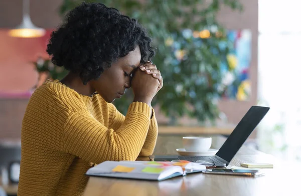 Chica africana agotada sentado en la cafetería, en busca de trabajo en línea —  Fotos de Stock