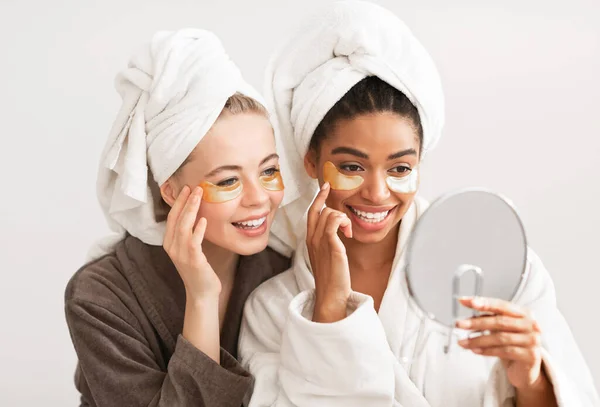 Piacevoli giovani donne con macchie sugli occhi guardando lo specchio — Foto Stock