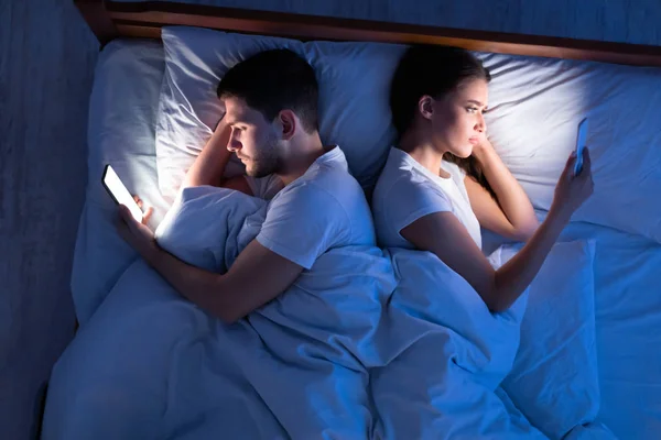 Εξαπάτηση συζύγους χρησιμοποιώντας Smartphones που βρίσκονται στο κρεβάτι τη νύχτα, Top-View — Φωτογραφία Αρχείου
