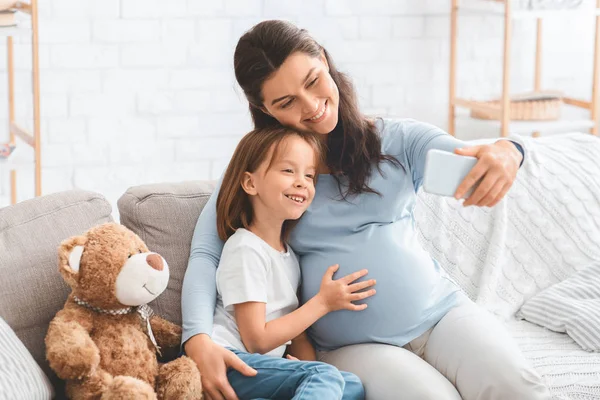 Feliz mujer embarazada tomando selfie con su hija pequeña — Foto de Stock