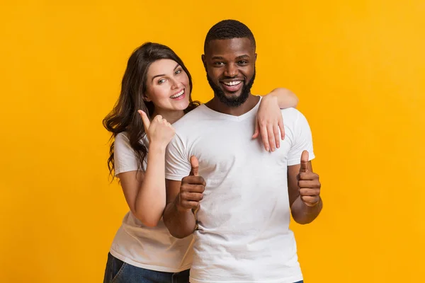 Glückliches Millennial-Paar umarmt und gestikuliert Daumen hoch in die Kamera — Stockfoto