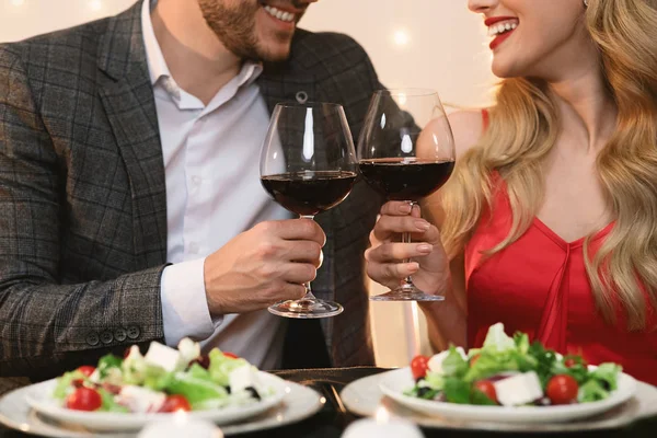 Pár csattogó vörösbor szemüveg a romantikus dátum az étteremben, közelkép — Stock Fotó