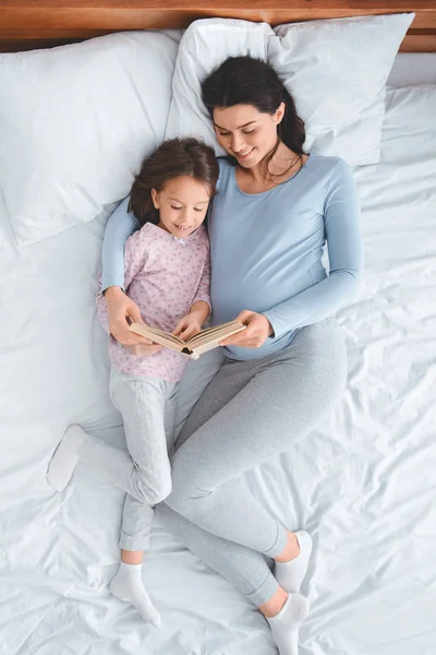 Top view of young expecting mom reading book to daughter — Stok Foto