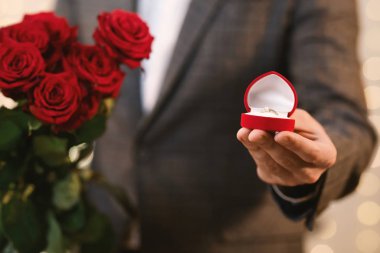 Elinde elmas yüzük ve gül buketi olan tanınmamış bir adam.
