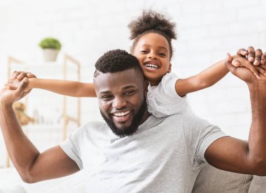 Yakışıklı siyah baba ve uçak taklidi yapan küçük kız.