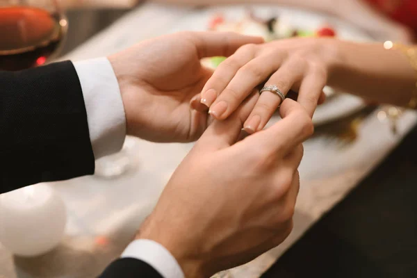 Homme mettant bague de fiançailles sur la main des copines pendant le dîner au restaurant — Photo