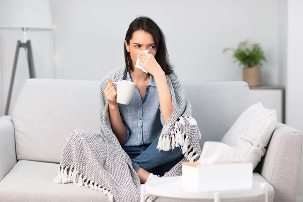 Άρρωστη γυναίκα τυλιγμένη σε κουβέρτα πίνοντας ζεστό καφέ — Φωτογραφία Αρχείου