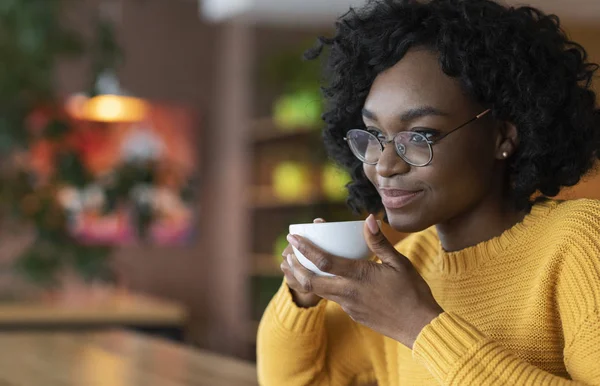 Dromerige jonge zwarte dame genieten van een kopje koffie in cafe — Stockfoto