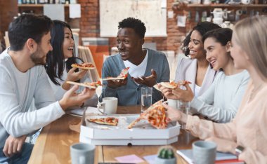 Uluslararası bir grup iş arkadaşı birlikte pizza yiyor.
