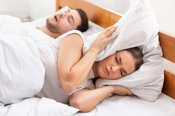 Unglückliche Freundin versucht, neben schnaubendem Freund drinnen zu schlafen — Stockfoto