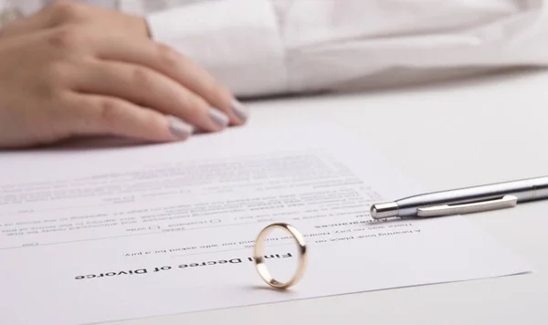Vrouw tekent echtscheidingsdecreet, trouwring ligt op document — Stockfoto