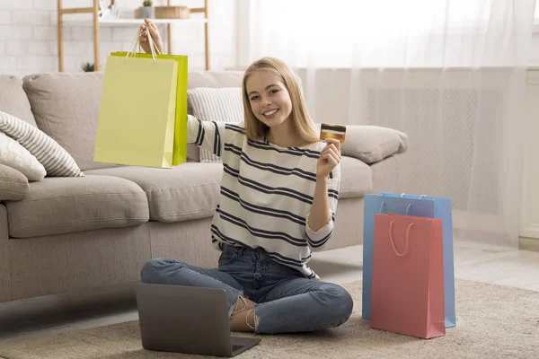 Jovencita alegre sosteniendo colorida bolsa de compras y tarjeta de crédito — Foto de Stock