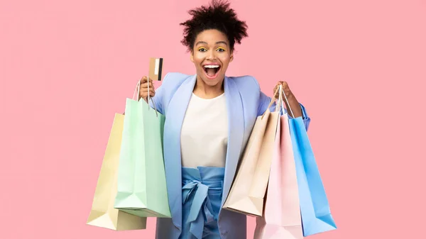 Mujer negra alegre con bolsas de compras y tarjeta de plástico —  Fotos de Stock