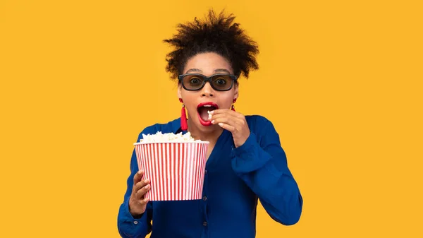 Удивлённая чёрная девушка с попкорном смотрит в камеру — стоковое фото