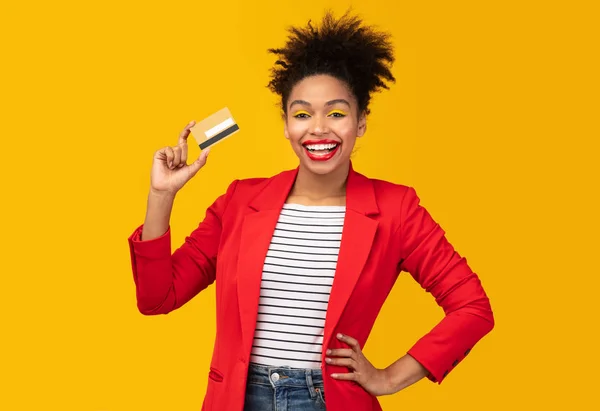 Afro woman holding credit card and looking at camera — стокове фото