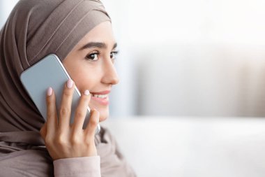 Cep telefonuyla konuşan ve yüzünü çeviren Müslüman kadının yakın plan portresi