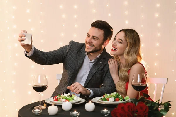 Szerető fiatal pár csinál Selfie, miközben étkezés étteremben — Stock Fotó
