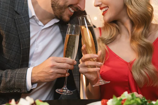 Copos de champanhe em mãos de casal irreconhecível no jantar romântico — Fotografia de Stock